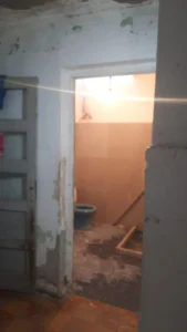 A simple bathroom featuring a toilet and a closed door, emphasizing a clean and functional design.