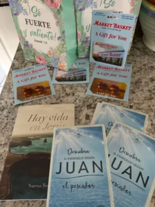 A stack of three books beside a bag filled with additional books on a wooden surface.