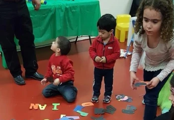 A group of children joyfully playing with colorful letters and numbers spread out on the floor, fostering early learning