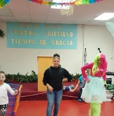 Children joyfully dancing in a room alongside women, creating a lively and cheerful atmosphere